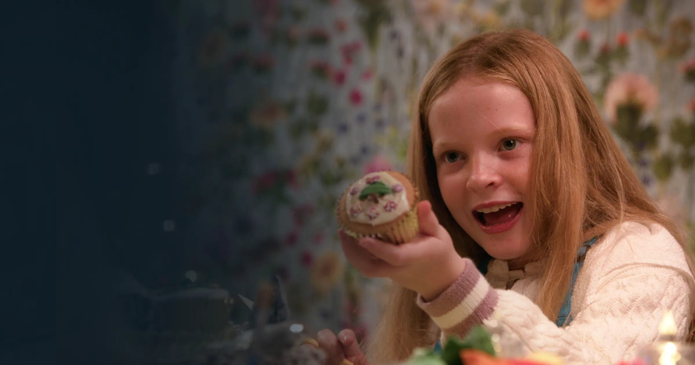Smiling girl holding a cupcake, with a playful, floral background. Buttons below say. Bright, cheerful vibe.